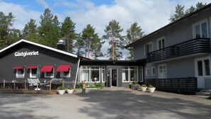 A building with a sign reading "Gästgweriet" and a covered outdoor seating area with tables and chairs. - Hotel Vuollerim (Vuollerim)