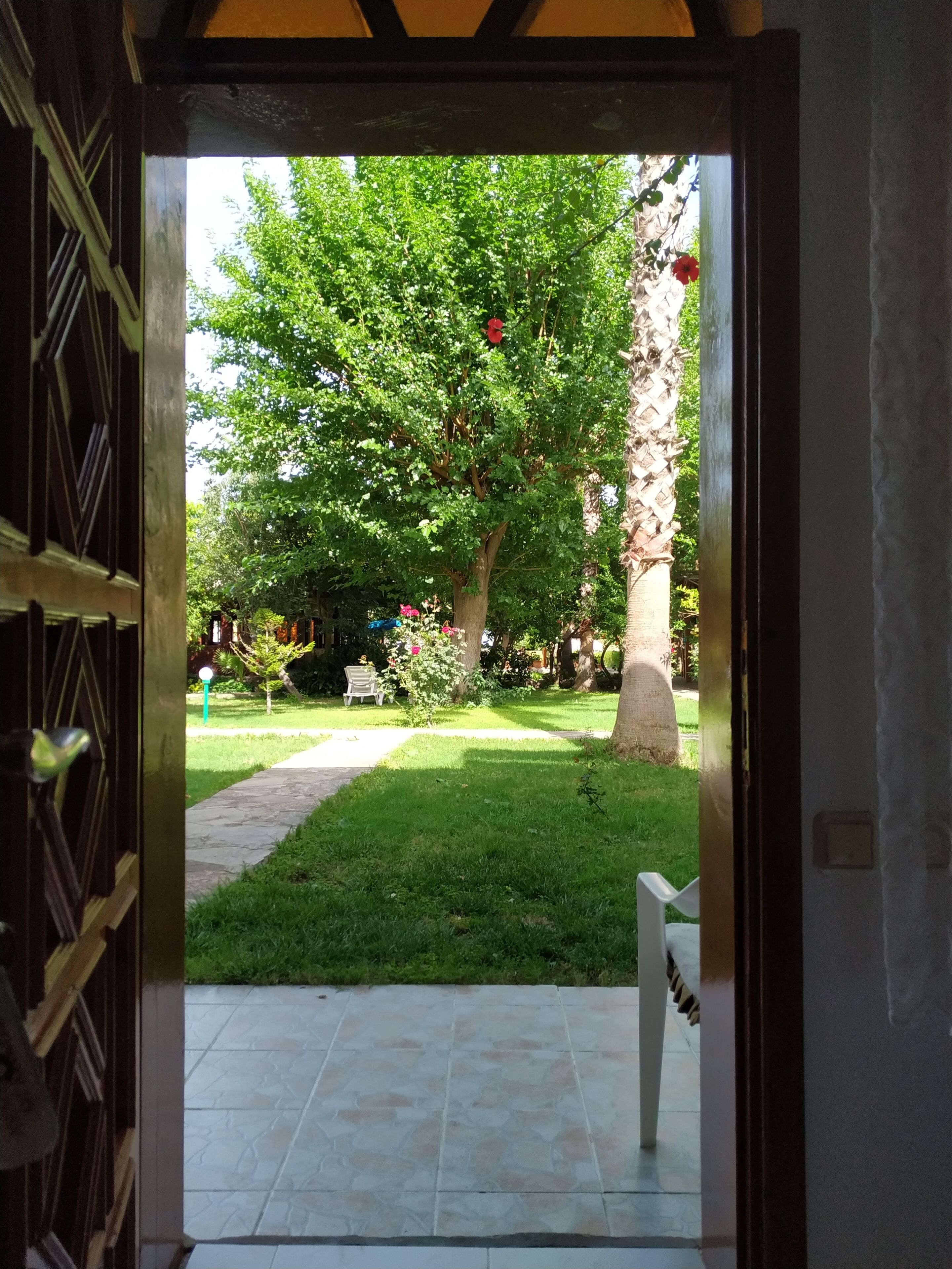 Una entrada que da a un jardín con césped, un camino de piedra y un banco.