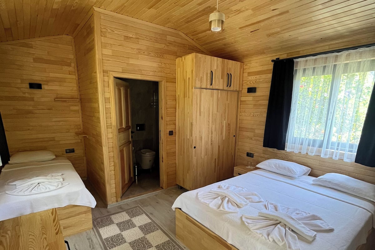Ein schlichtes Schlafzimmer im Blockhausstil mit zwei Betten, einem Kleiderschrank und einem kleinen Badezimmer.