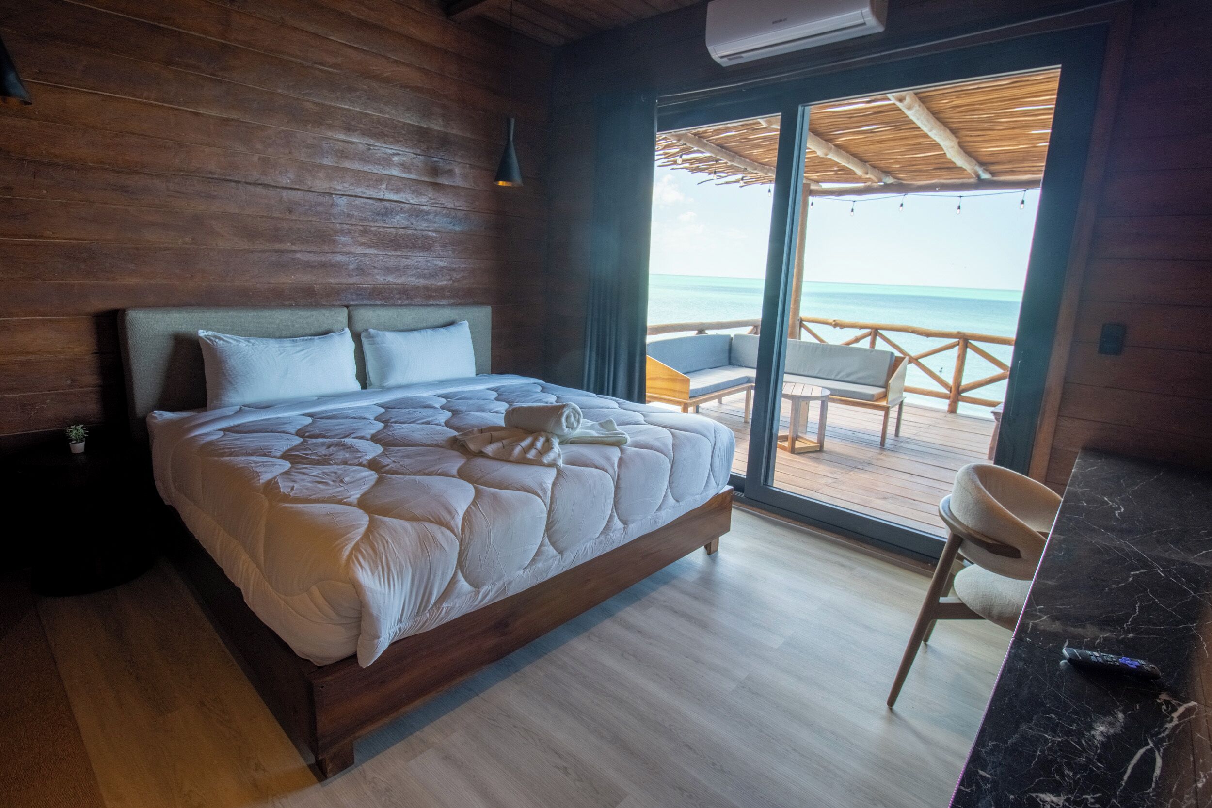 Une pièce en bois avec un lit, une chaise et une vue sur l’océan.