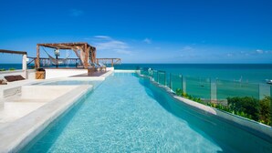 Una piscina infinita con agua azul cristalina, una terraza de madera y vistas al océano.