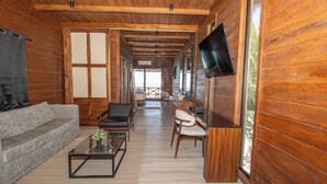 Un interior de madera con un sofá, sillones, una mesa de centro y un televisor.