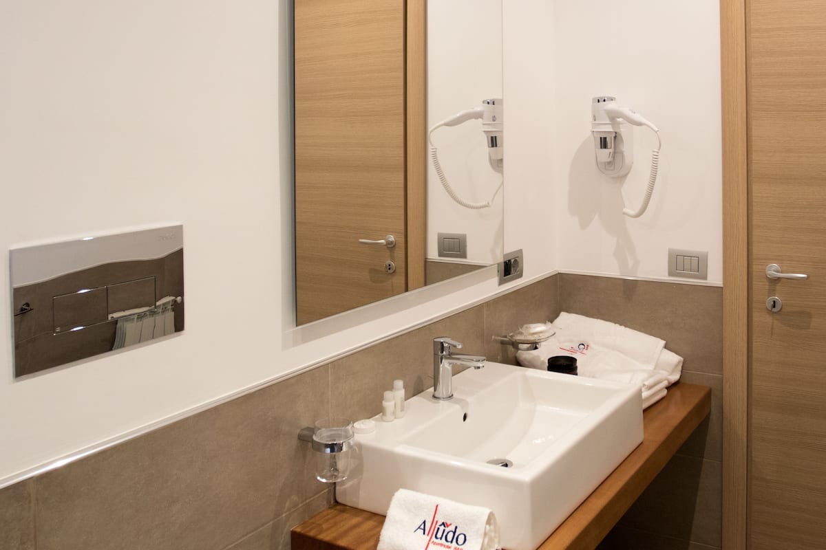 Un baño moderno con un espejo grande, dos lavamanos, un perchero para toallas y un secador de pelo.