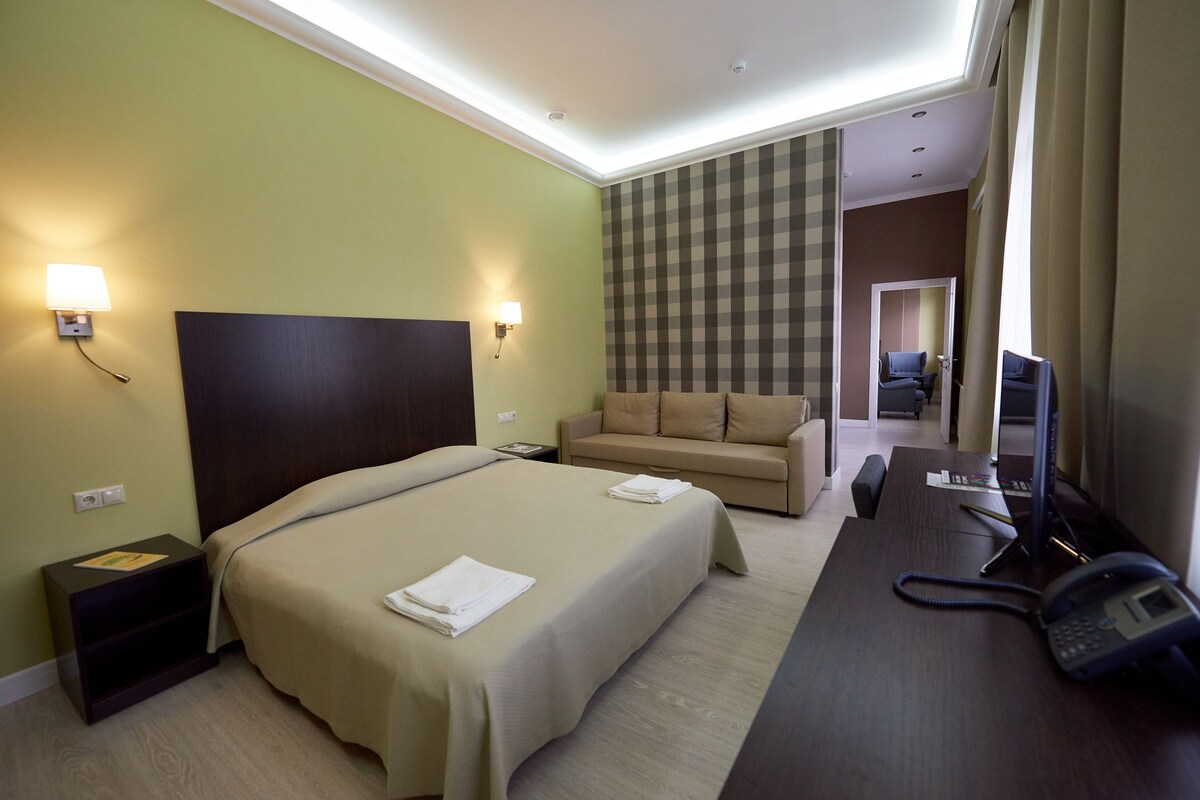 Une chambre d’hôtel comprenant un lit, un canapé, un bureau avec un téléphone et une télévision.