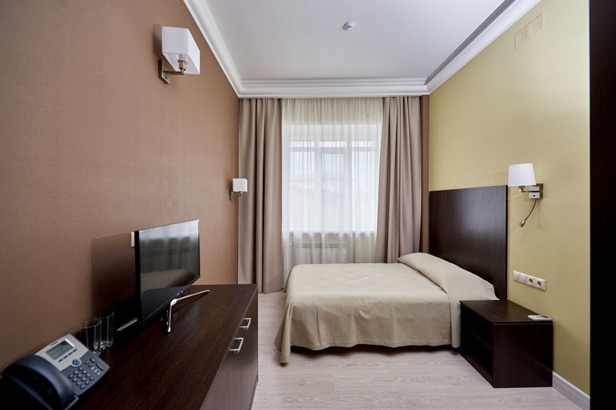 Une chambre d’hôtel comprenant un lit, un bureau avec un téléphone, une télévision et une lampe.