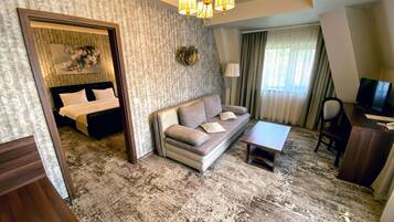 A hotel room with a bed, sofa, TV, and a small table.