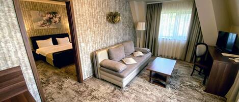 Ein Hotelzimmer mit Bett, Sofa, Fernseher und kleinem Tisch.