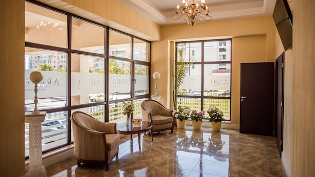 Un vestíbulo amplio con ventanas grandes, un candelabro y un mostrador de recepción.