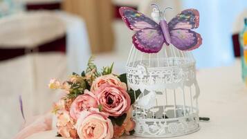Una jaula blanca con un adorno de mariposa morada y un ramo de rosas rosas.