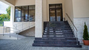 Entrada de un edificio con una escalera que lleva a una puerta marcada 'ARMIA'.