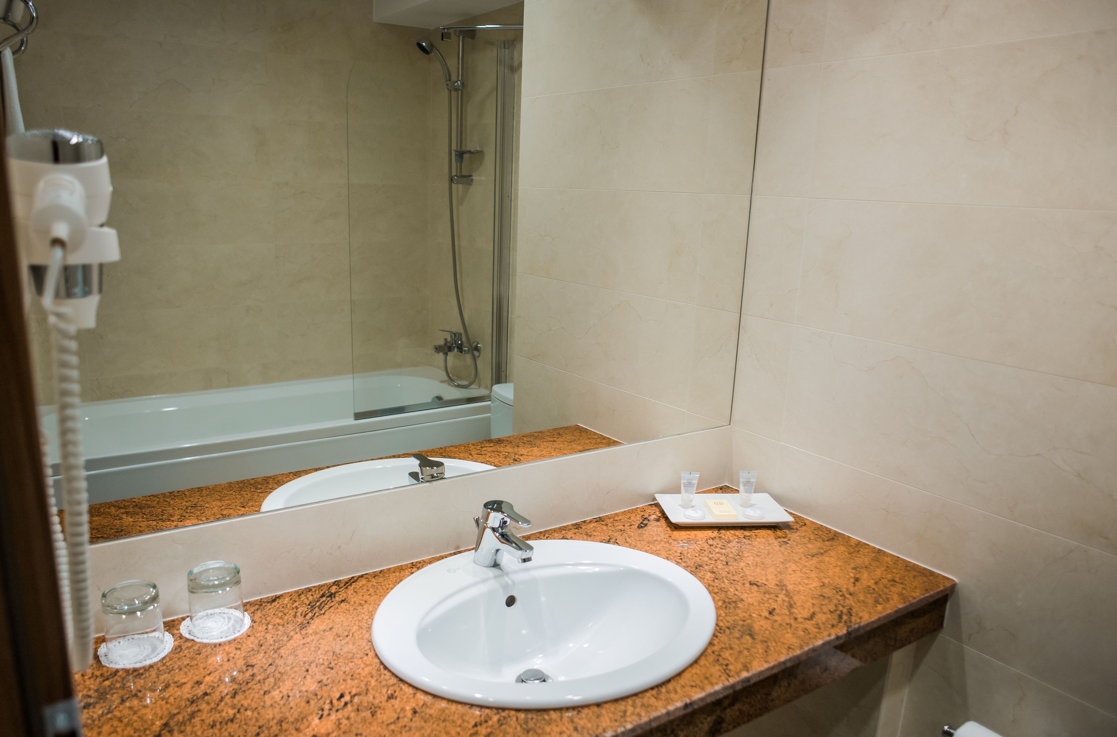 A bathroom with a white sink, granite countertop, and a large mirror.
