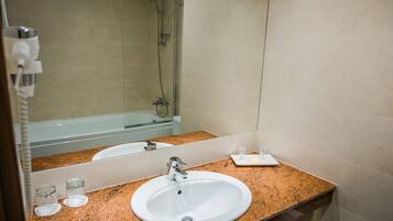 A bathroom with a white sink, granite countertop, and a large mirror.