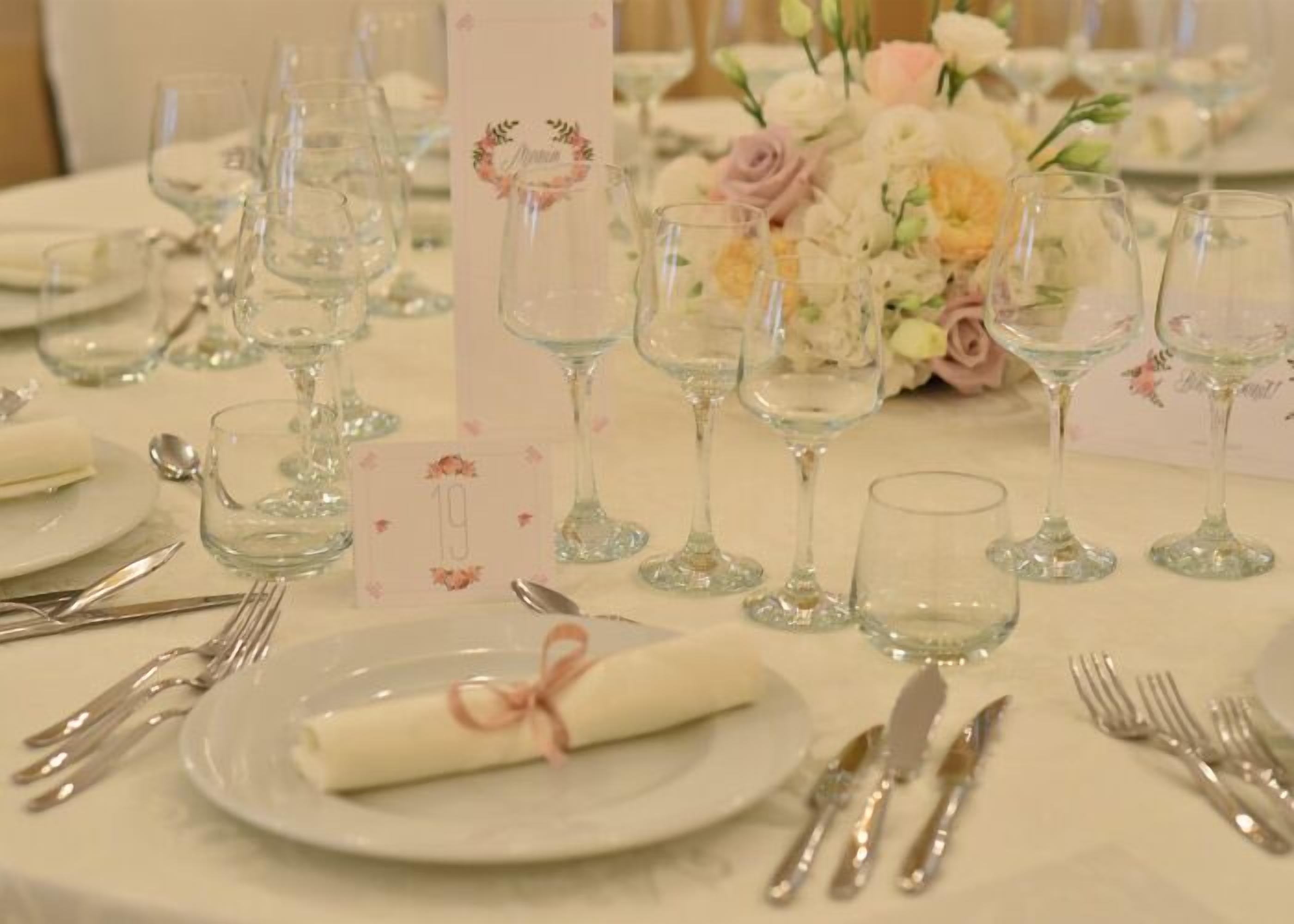 A table set for a formal event with clear glassware, a folded napkin, and a floral centerpiece.