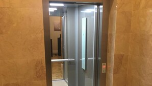 Un ascensor moderno con puerta de cristal y suelo de mármol.