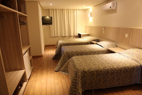 A hotel room with two beds, a TV, and a wardrobe. - Golden Hotel (Chapecó)