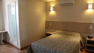 Un dormitorio con cama, mesitas de noche, armario y unidad de aire acondicionado.
