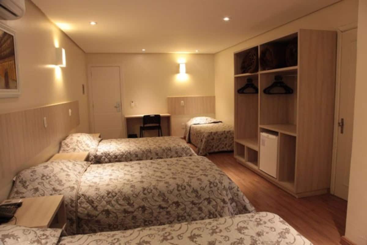 A hotel room with two beds, a desk, and a wardrobe.