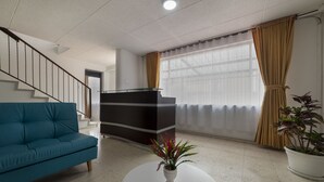 A modern living room with a blue sofa, a white coffee table with a plant, a dark-colored cabinet, and a staircase.