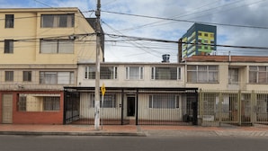 A multi-story building with a gated entrance and a visible signpost.