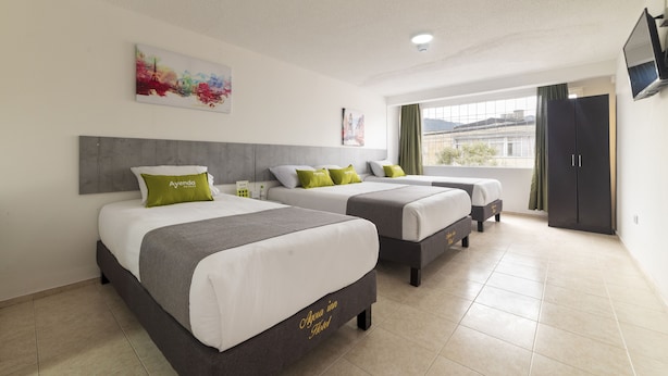 A hotel room with two beds, a large window, a painting on the wall, and a television mounted on the wall.