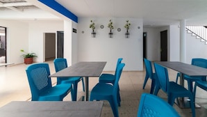 A modern indoor space with blue chairs and tables, a staircase, and potted plants on the wall.