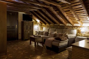 Um quarto de sótão aconchegante com teto de madeira, um sofá, uma mesa e uma televisão.