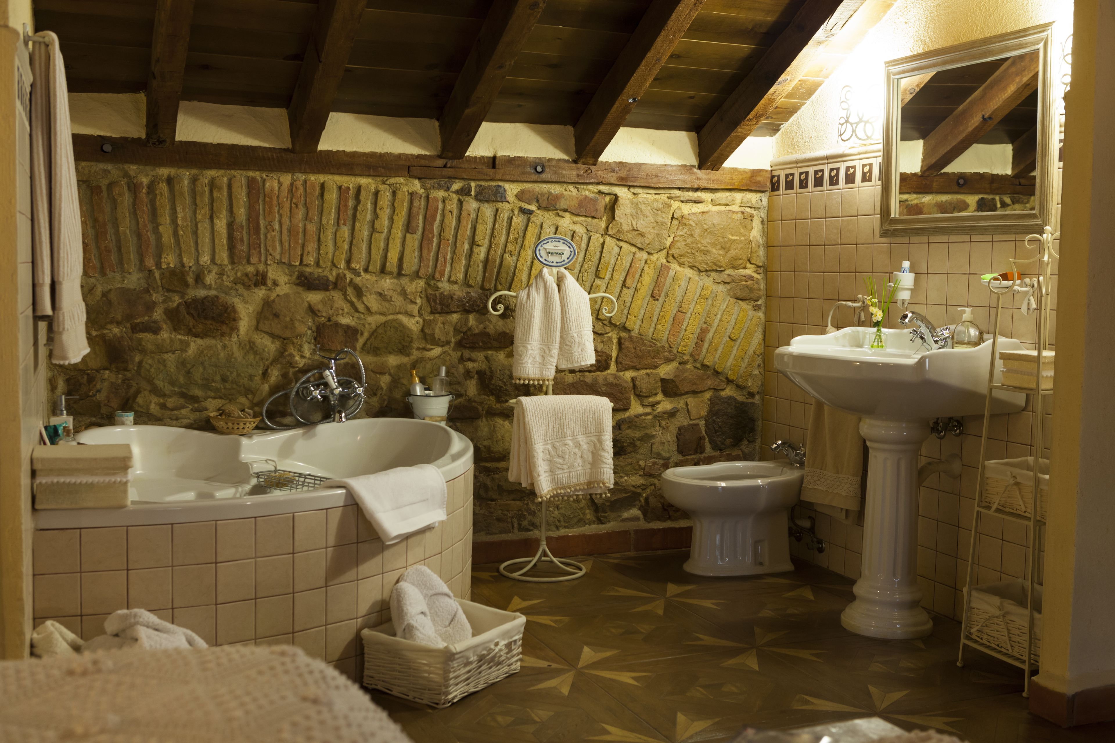 Un baño con pared de piedra, una bañera, un lavamanos y un inodoro.