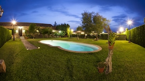 Ein gepflegter Garten mit Schwimmbecken, umgeben von ordentlich geschnittenem Rasen und Bäumen.