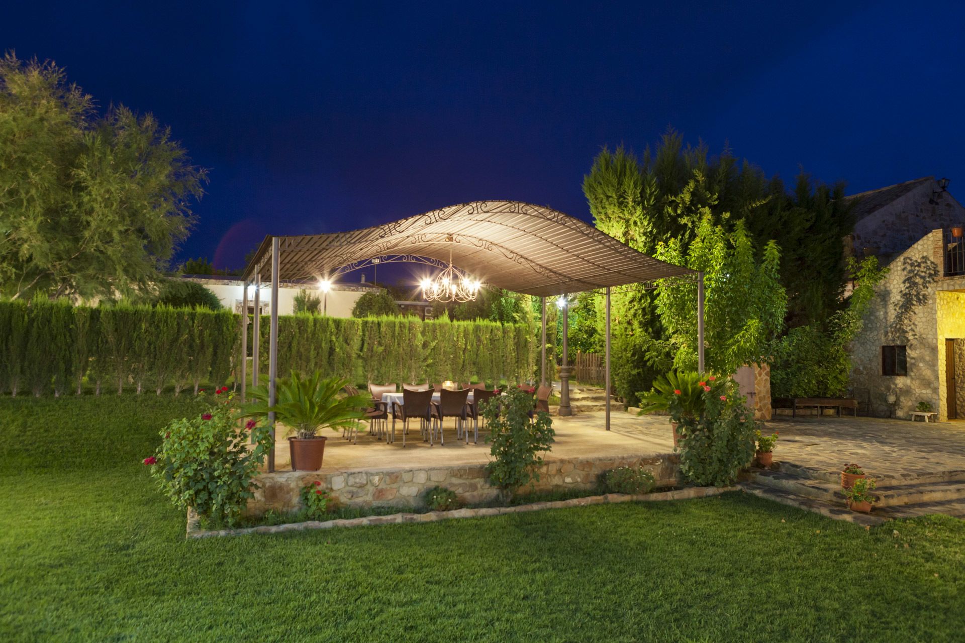 An outdoor patio area with a covered seating arrangement, stone flooring, and potted plants.