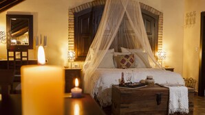 Ein Schlafzimmer mit Himmelbett, einem hölzernen Truhe und einer brennenden Kerze.