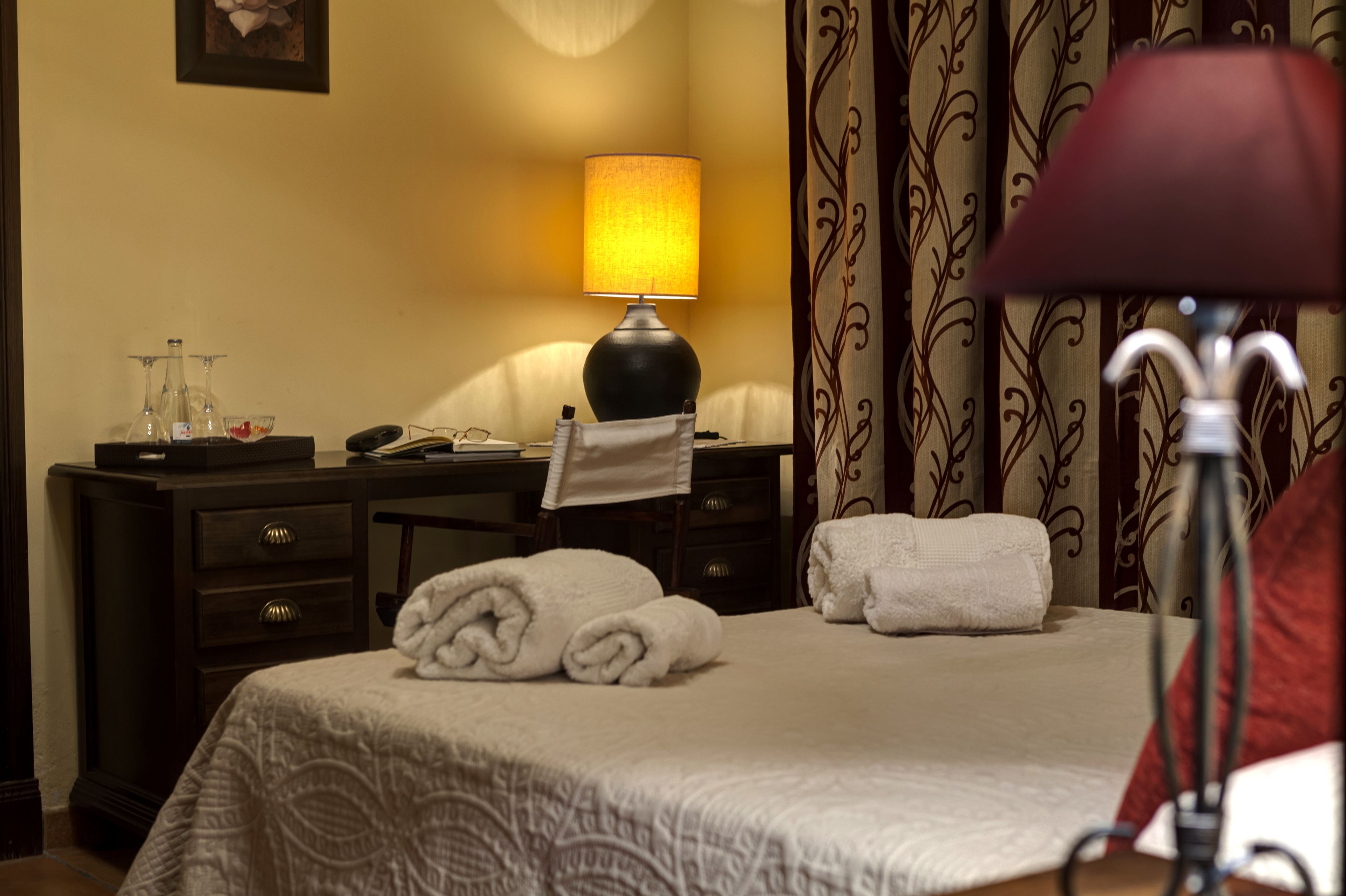 Une chambre d’hôtel avec un lit, un bureau, une lampe et une chaise.