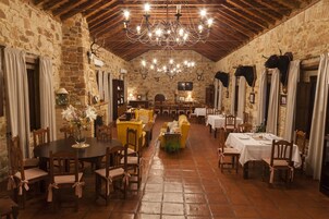Uma área de refeições rústica com paredes de pedra, móveis de madeira e um candelabro.