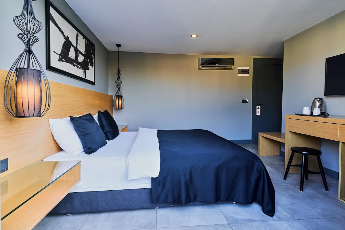 Una habitación de hotel moderna con cama, mesita de noche, escritorio y silla.