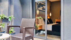 A modern room with a glass door leading to a balcony, wicker furniture, a bed, and a hanging light fixture. - Loft 1502 (Antalya)