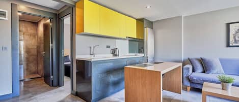 Una cocina moderna con armarios amarillos, una isla integrada y un sofá gris en la zona de estar.