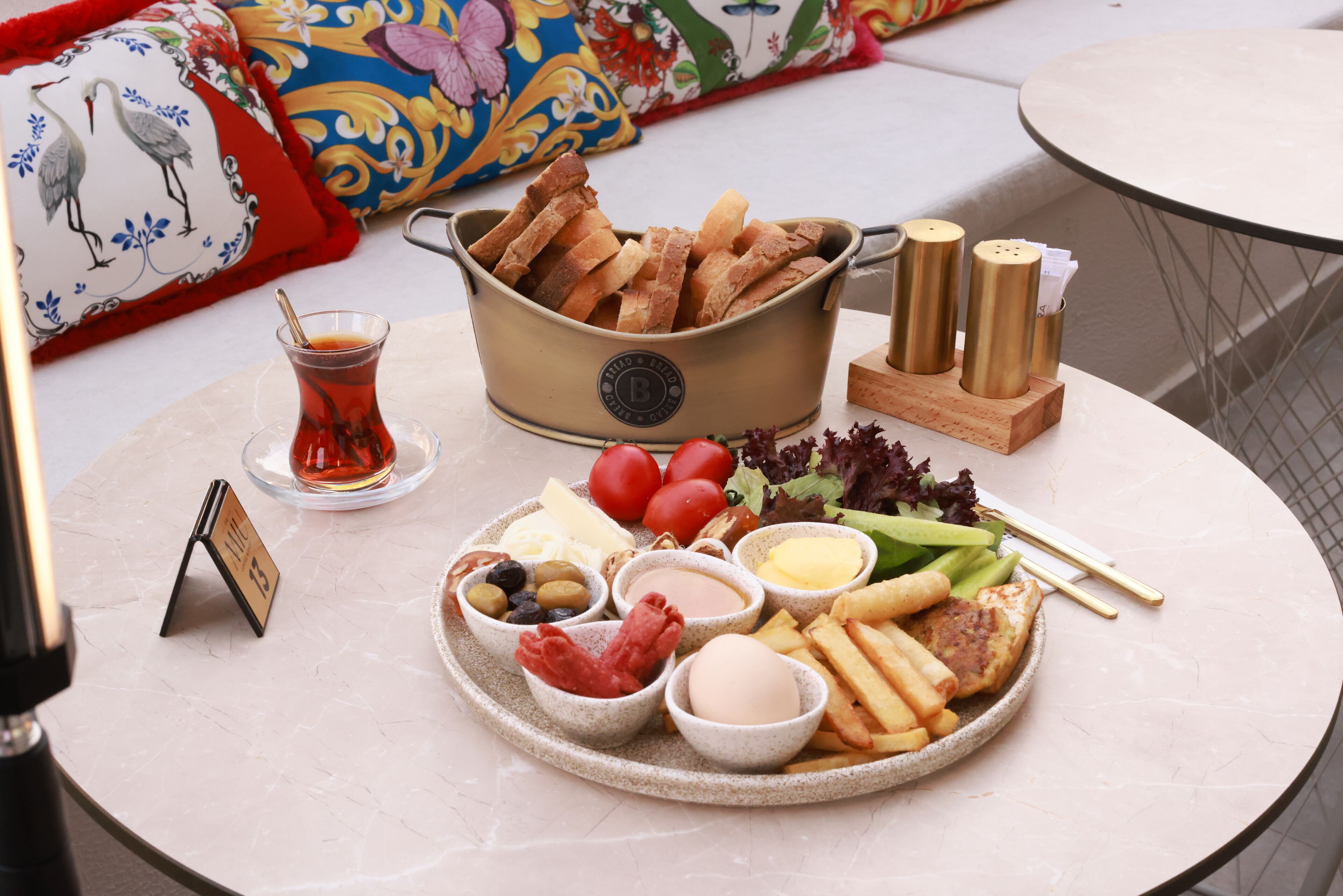 Ein Tisch reichhaltig gedeckt mit verschiedenen Speisen, darunter Brot, Tomaten, Käse, Oliven und Gewürzen.