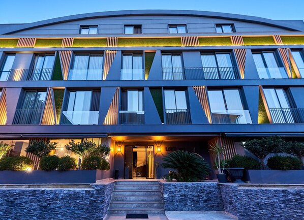 A modern hotel with a curved facade, large windows, and a well-lit entrance.