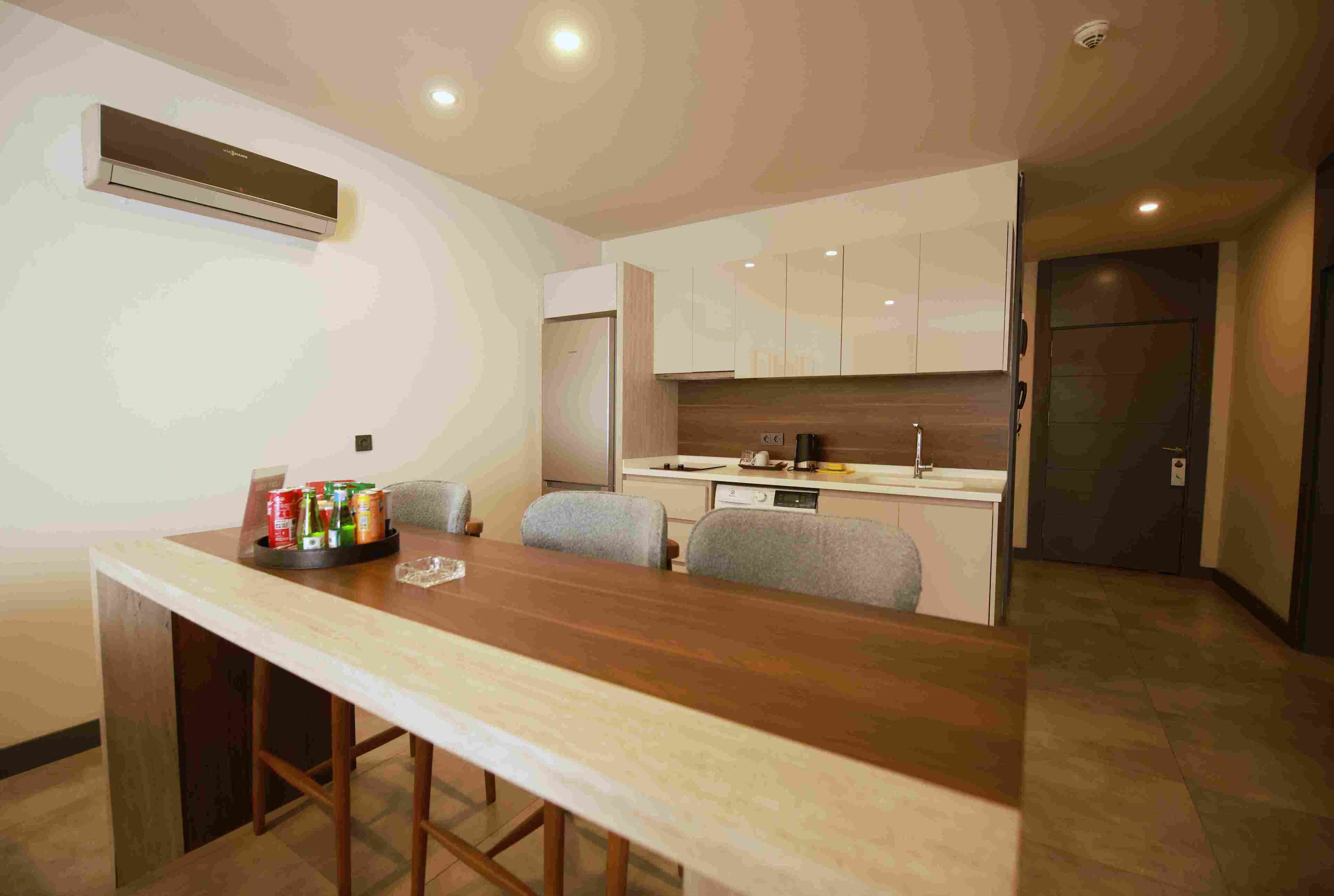 A modern kitchen with a central island, built-in cabinets, and a dining area with a long table and chairs.