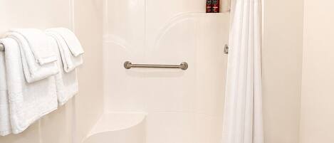 Un baño pequeño y blanco con ducha, inodoro y perchero para toallas.
