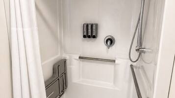 A white shower stall with a handheld showerhead, a handheld shower control, and a grab bar.
