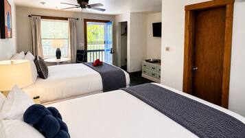 A hotel room with two beds, a ceiling fan, a balcony, a dresser, and a door.