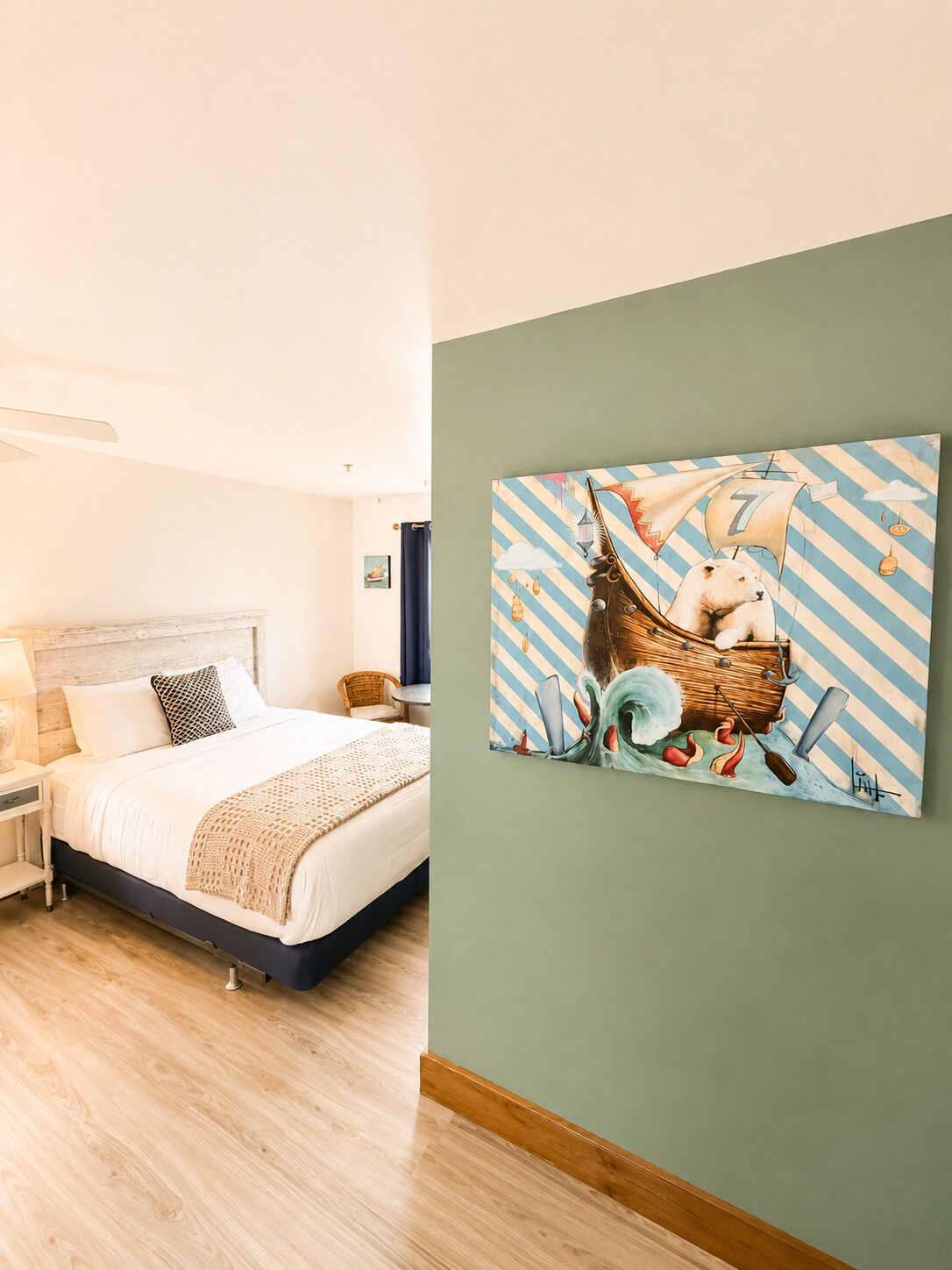 A bedroom with a bed, a nightstand, a lamp, a chair, and a wall with a painting.