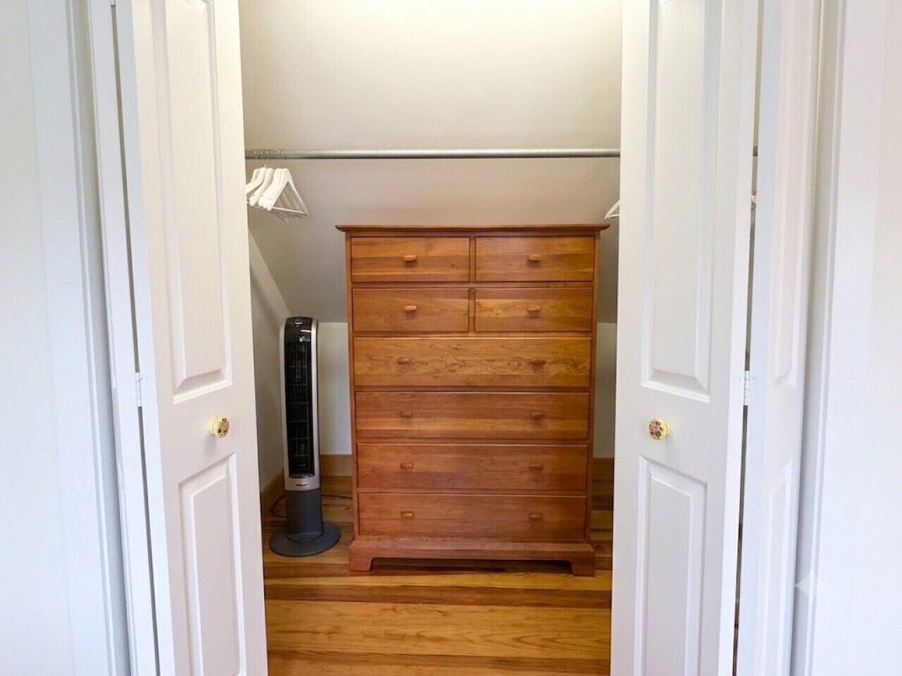 A narrow hallway with a wooden dresser and a standing heater.
