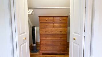 A narrow hallway with a wooden dresser and a standing heater.