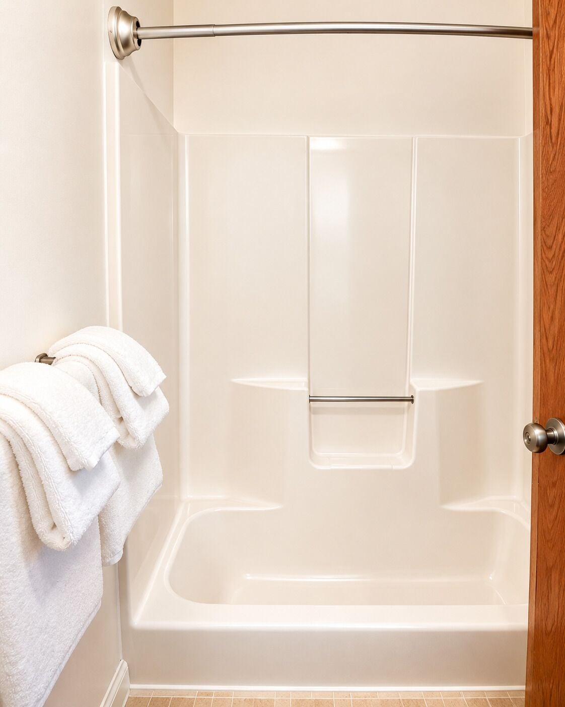 A bathroom with a bathtub, a towel rack with towels, and a wooden door.