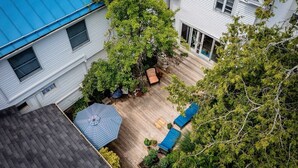 Ein Wohngebiet mit einer Holzterrasse, einem blauen Sonnenschirm und einem Baum.