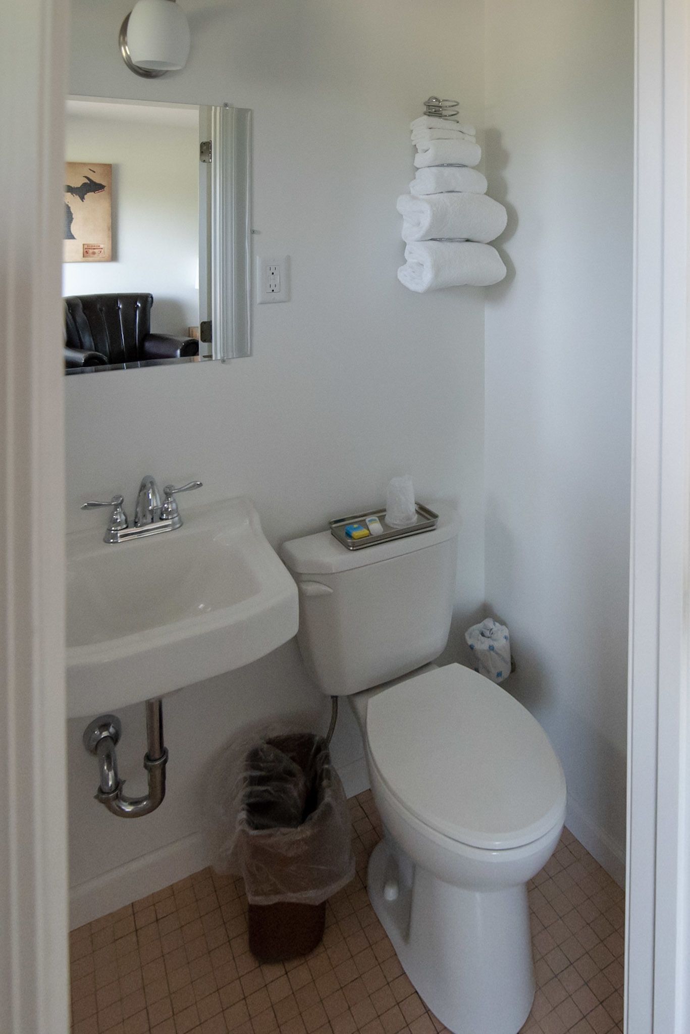 A bathroom with a white sink, toilet, and a trash bin.