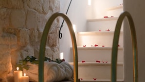 A spa area with a stone wall, a pool, and a set of stairs with rose petals.