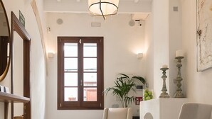 A spacious living area with a high ceiling, a large window, and a modern chandelier.