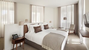 Ein Hotelzimmer mit einem großen Bett, Nachttischen, einem Schreibtisch und einem Sessel.